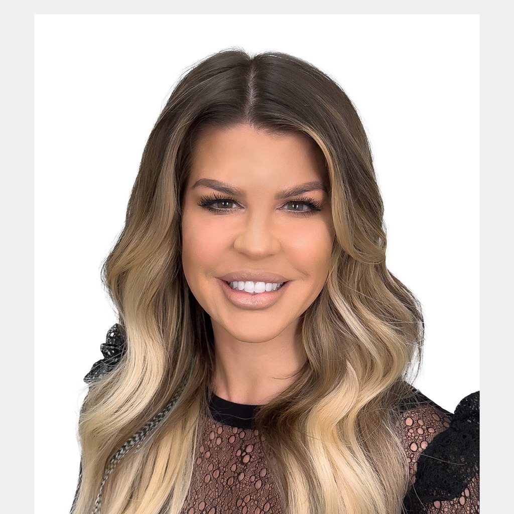 40. Female program director. Smiling woman with long blonde hair, wearing a black lace top, set against a solid black background