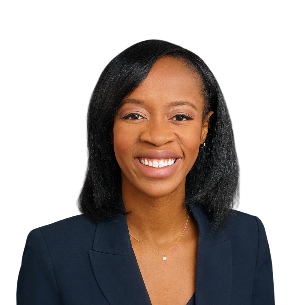 43. Female ECD. Smiling Black woman in a dark blazer against a plain gray background