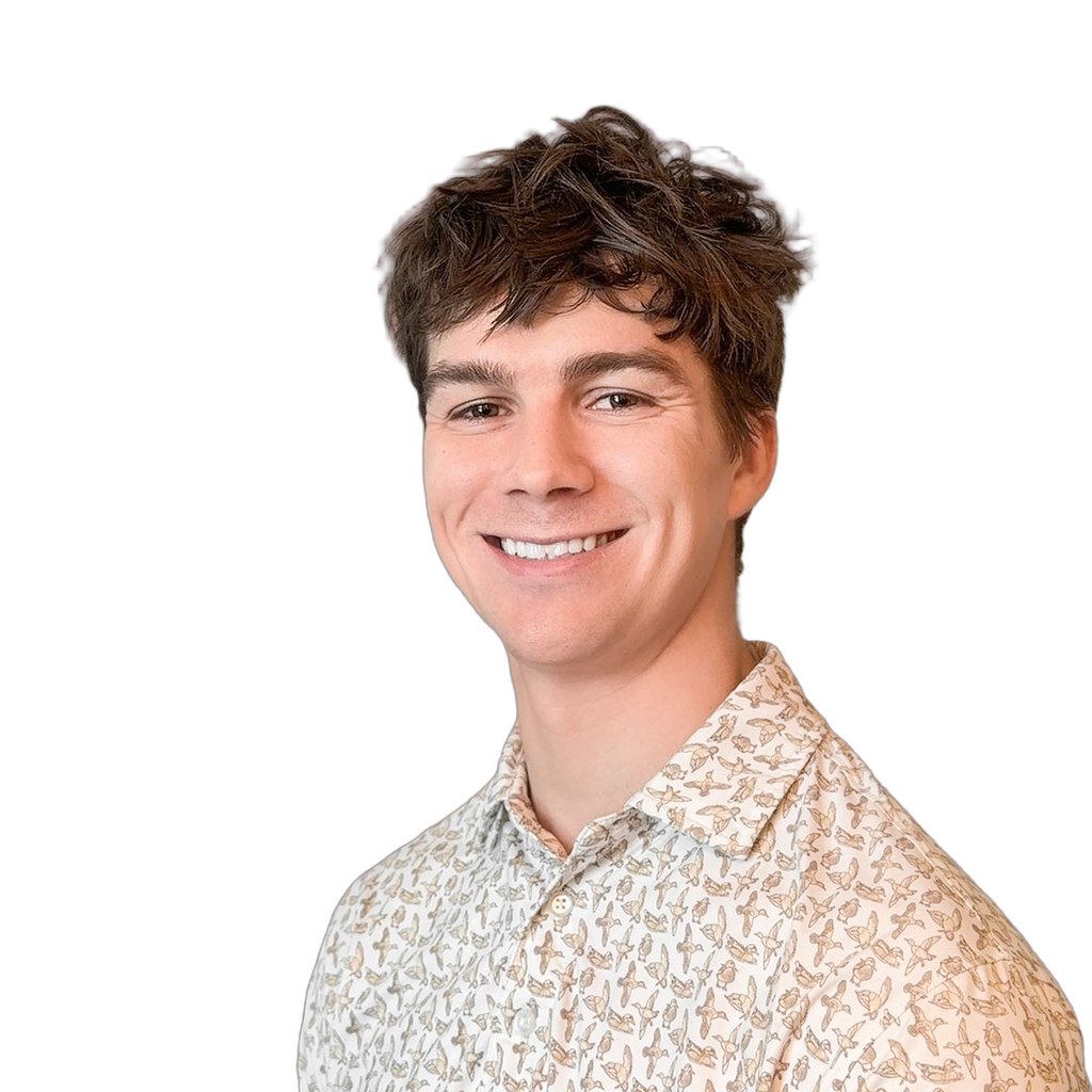 45. Copywriter. Young adult male with a toothy smile wearing a patterned button-down shirt against a solid coral background