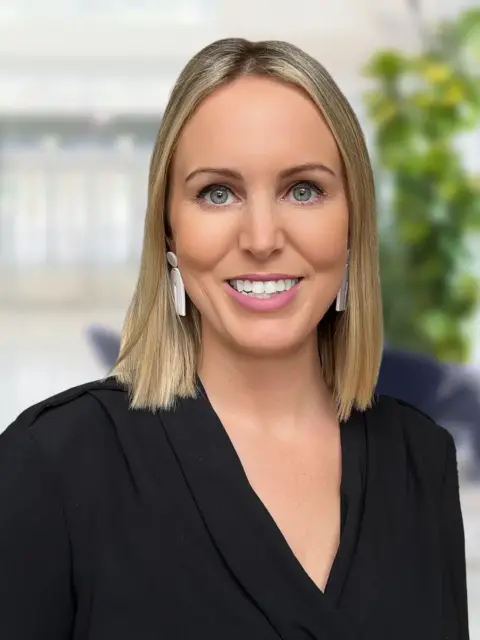 A woman with blonde hair and earrings, looking elegant and stylish.