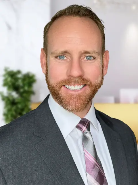 A bearded man in a tie working in an office.