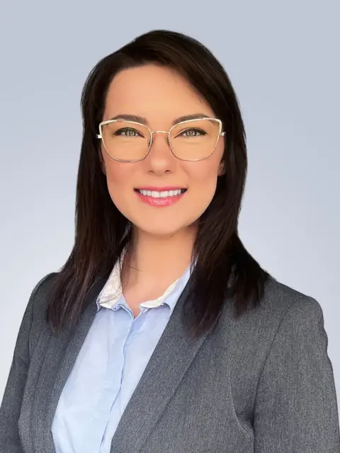 A professional woman wearing glasses and a suit, striking a pose for a photograph.