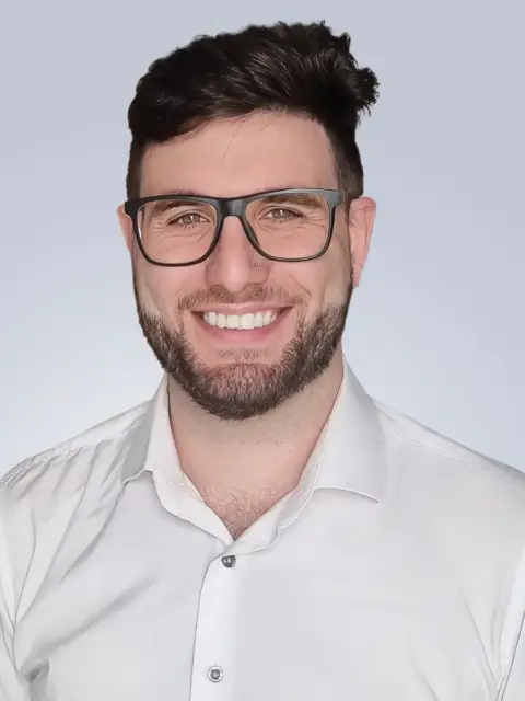 A man wearing glasses and a white shirt.