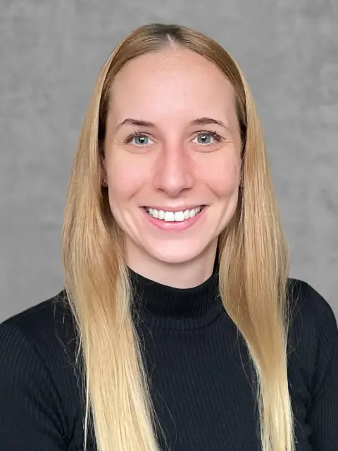 A woman with long blonde hair smiling, radiating warmth and happiness.