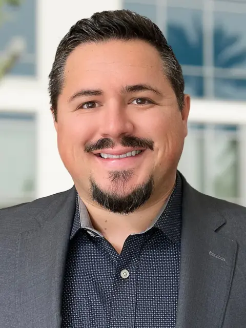 A well-groomed man wearing a suit jacket and sporting a beard, exuding professionalism and style.